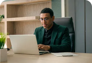 Dueño de empresa en un escrito con una computadora llenando un formulario de LAFISE.