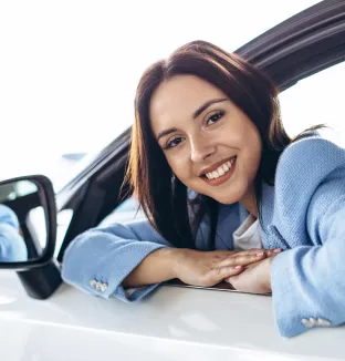 Chica sonriente en su auto con Crédito LAFISE